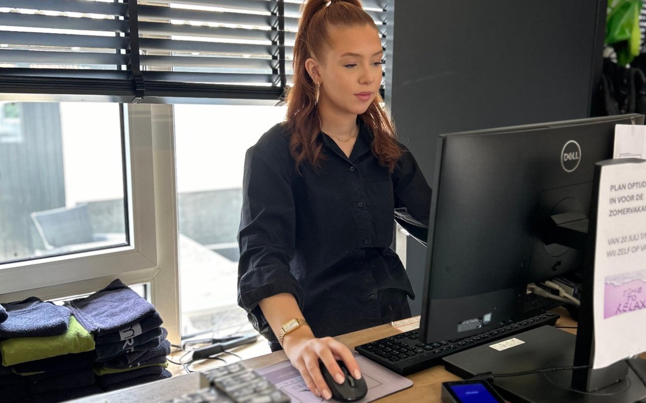 Een medewerkster achter de computer bij de balie van de salon